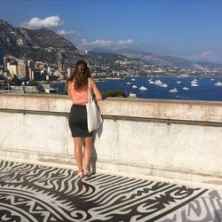 Rear view of woman standing at building terrace against cityscape