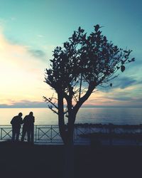 Silhouette people by sea against sky during sunset