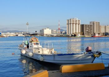 Boats moored in sea against buildings in city