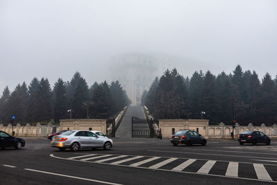 Cars on road against sky in city