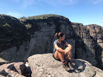 Woman sitting on rock against mountains