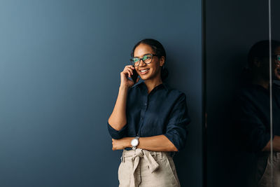 Businesswoman talking on phone while standing in office