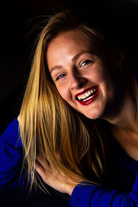 Portrait of laughing woman against black background