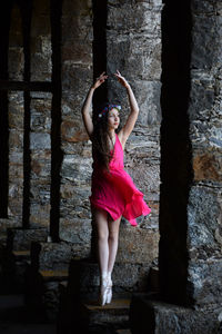 Beautiful ballet dancer posing against old column