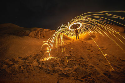 Man spinning wire wool on field at night