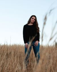 Young woman standing on field against sky