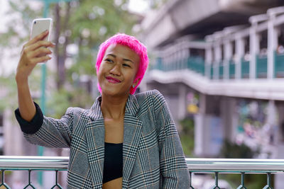 Portrait of smiling young woman using mobile phone outdoors