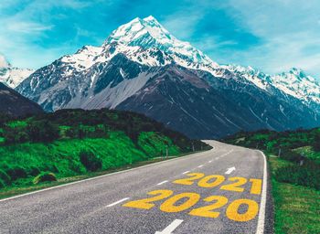 Road sign by snowcapped mountain against sky