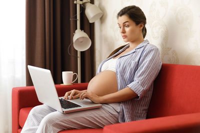 Smiling pregnant woman using laptop in office