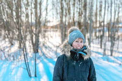 Portrait of woman in snow against trees during winter