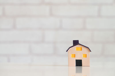 Close-up of model house on table against brick wall