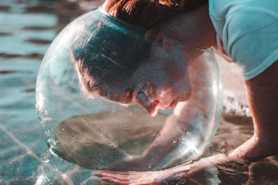 Close-up of woman wearing glass container at lake