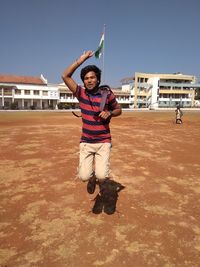 Portrait of young man jumping on land against built structure