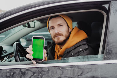 Millennial man drive the car and using mobile app , green screen. high quality photo