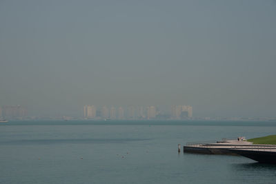 Scenic view of sea and buildings against clear sky