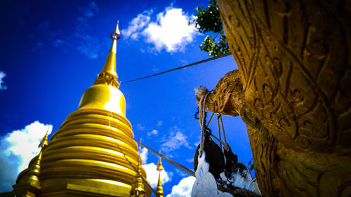 Low angle view of temple against building and blue sky