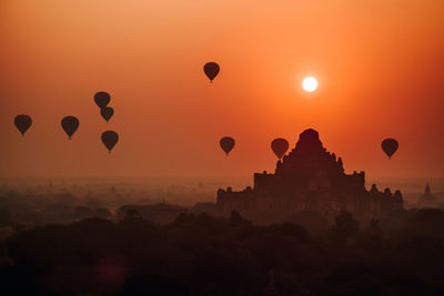 Silhouette of hot air balloons against sky during sunset