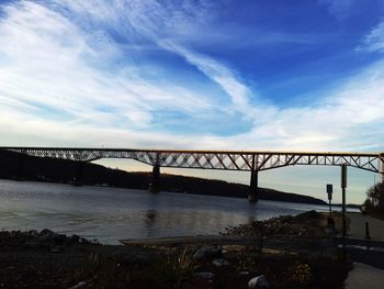 Bridge over river against cloudy sky