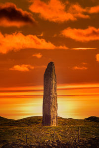 Scenic view of wooden post on field against sky during sunset