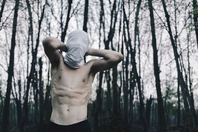 Low angle view of shirtless man in forest