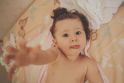 Portrait of cute baby girl lying on bed at home