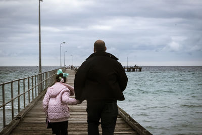 Rear view of people looking at sea against sky