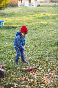 Portrait of a village boy child raking leaves in autumn at home
