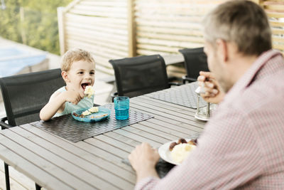 Father and son eating food while sitting at restaurant