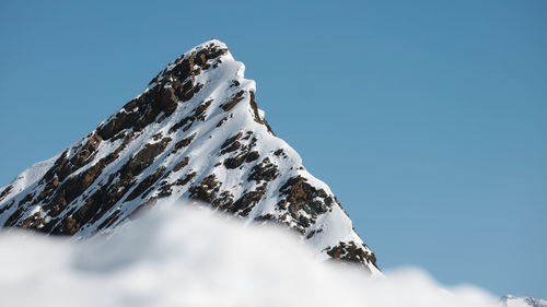 Low angle view of snowcapped mountain against clear blue sky