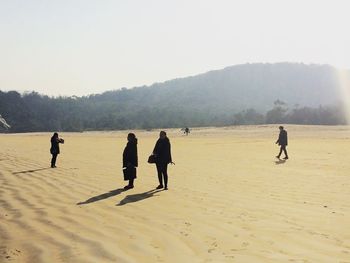 People on beach against clear sky