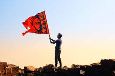 Full length of man holding flag against clear sky