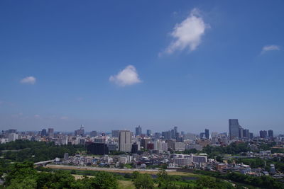 Aerial view of buildings in city against sky