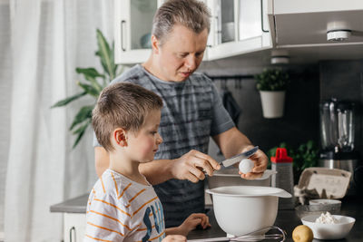 Man with boy preparing food in kitchen
