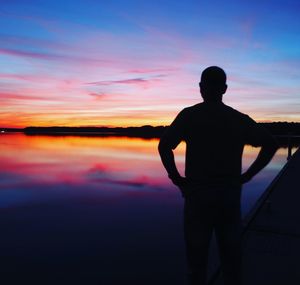 Silhouette man looking at sea against sky during sunset