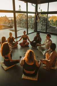 Multiracial female friends holding hands while meditating together at retreat center