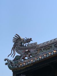 Low angle view of statue of building against clear blue sky