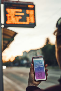 Buying ticket online near bus stop before ride. person paying for ticket using mobile payment app