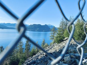 Scenic view of mountains seen through chainlink fence