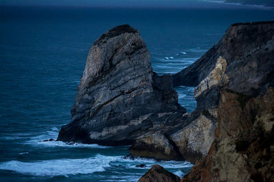 Rock formation in sea against clear blue sky