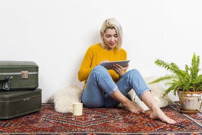 Portrait of young woman sitting on sofa against white background