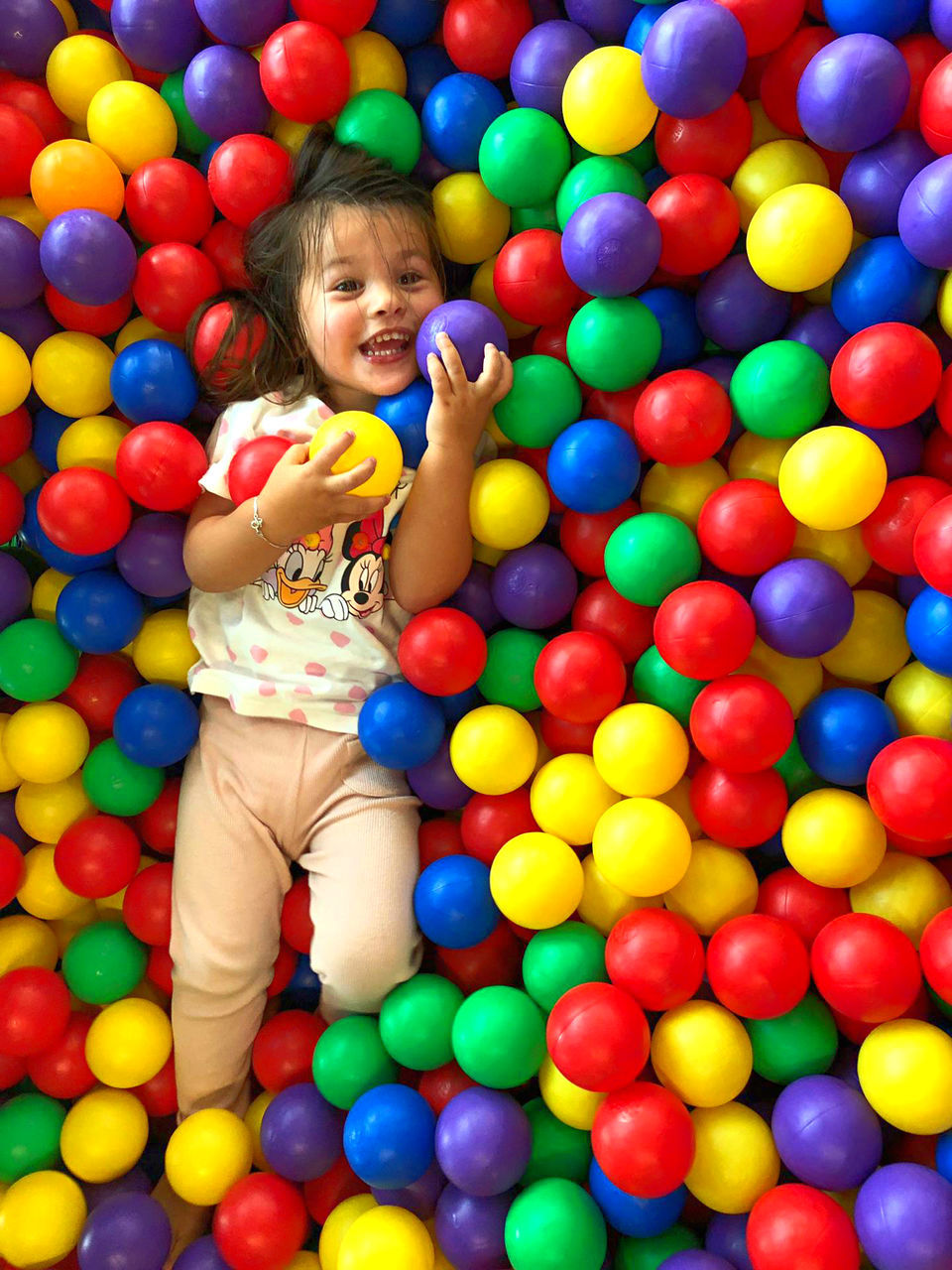 childhood, child, leisure activity, one person, enjoyment, fun, happiness, multi colored, playing, full length, ball, real people, smiling, emotion, girls, lifestyles, casual clothing, sphere, innocence, excitement