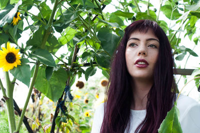 Portrait of young woman against plants