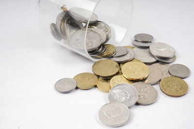 High angle view of coins spilling from container on white background