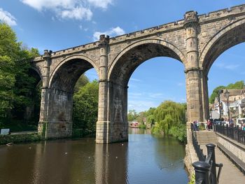 Arch bridge over river against sky
