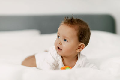 Cute baby looking away while lying down on bed