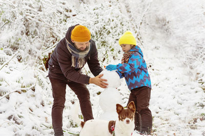 Father and son making snow man during winter