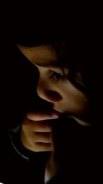 Close-up of young woman against black background