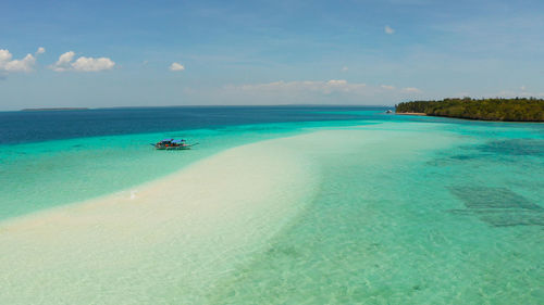 Sand bar and tropical island in the clear turquoise waters of the lagoon. mansalangan sandbar
