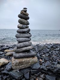 Stack of pebbles on beach against sky