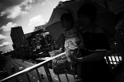 Low angle view of young woman in city against sky